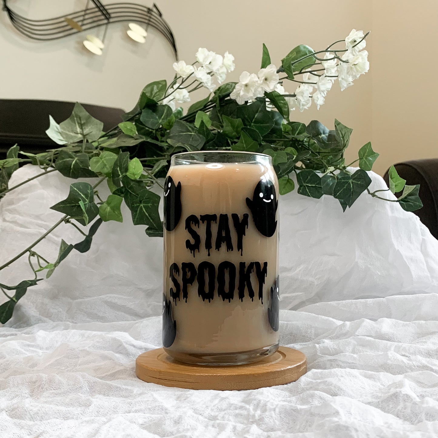 Cute Halloween beer can glass filled with iced coffee in front of a white and green background.