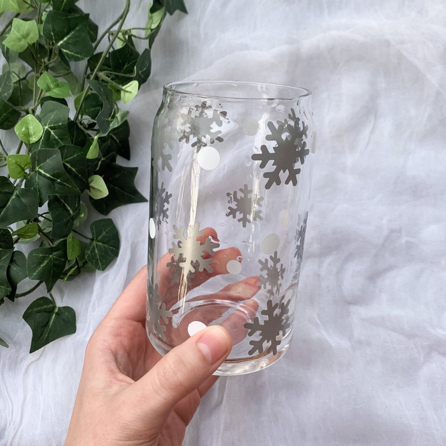 Hand holding a winter wonderland cup with silver snowflakes and white dots.