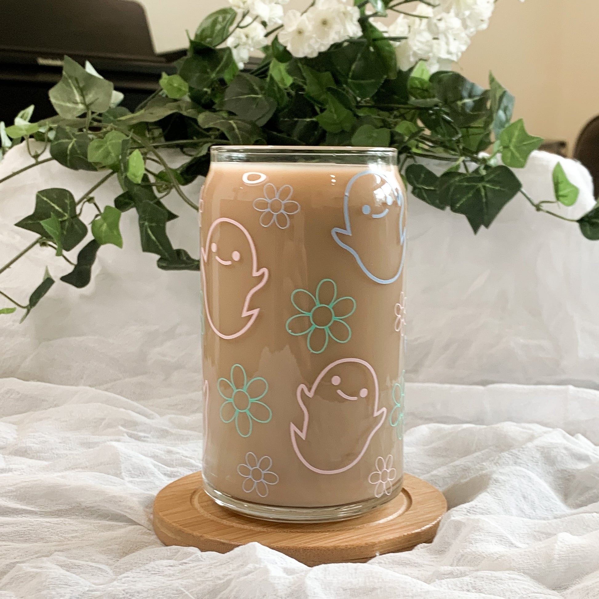 A Halloween iced coffee glass with pastels ghosts and flowers is full of delicious coffee.